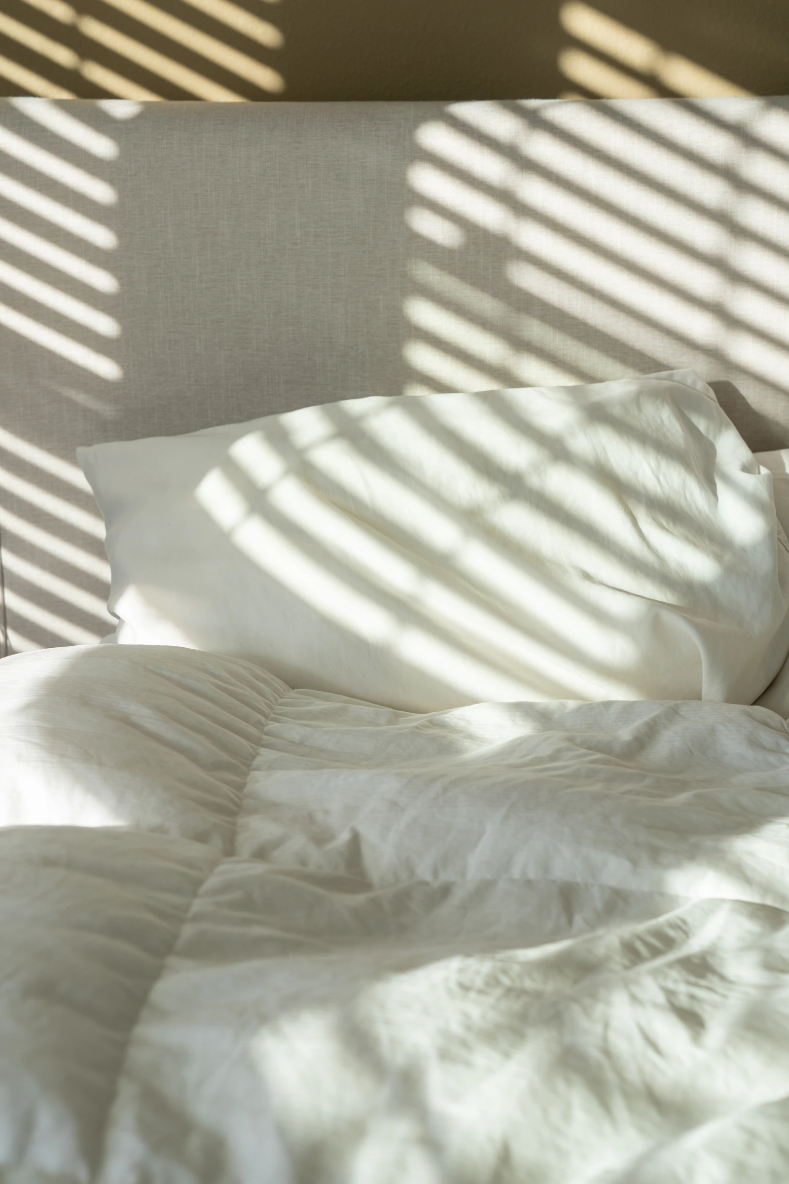 A made bed in a quiet, well-lit bedroom